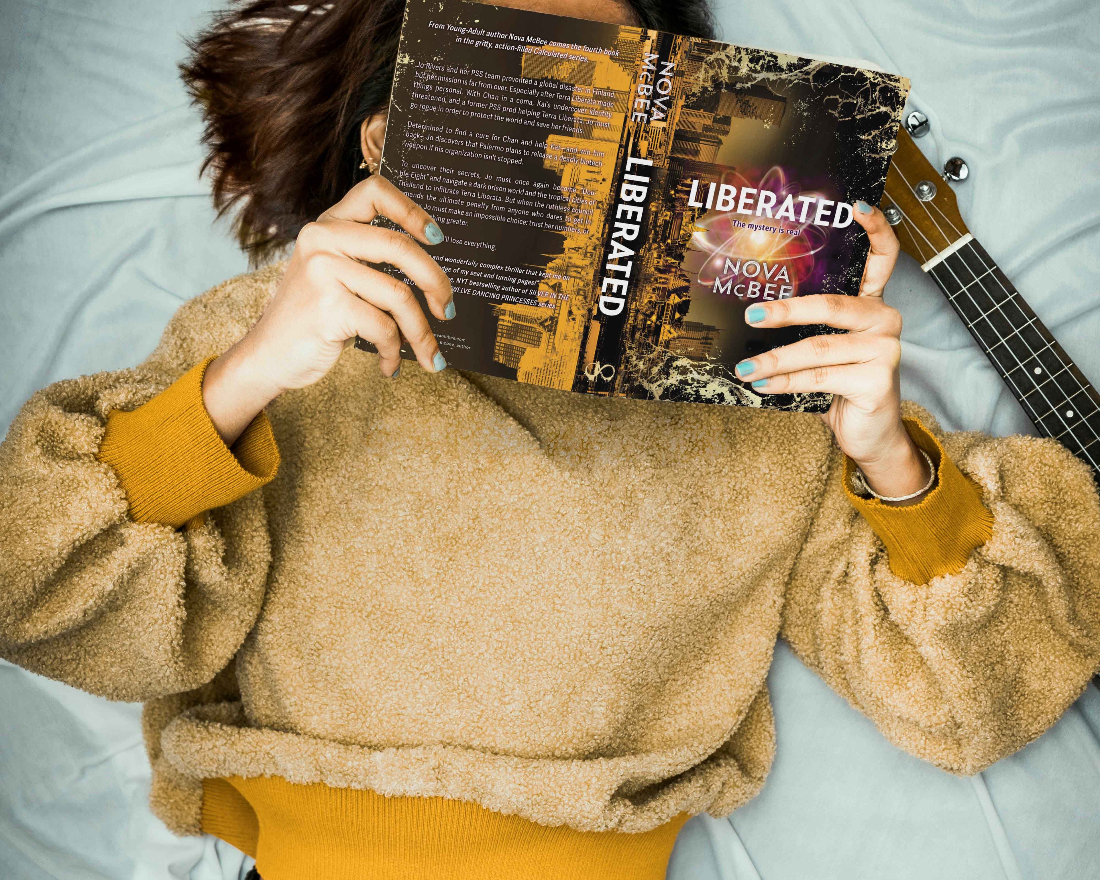 Person lying on a bed holding 'Liberated' album covers